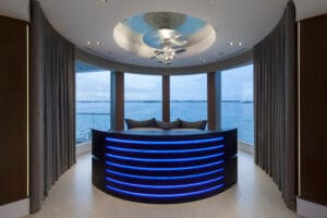 Main bedroom with rounded design, blue lights on the console framing the foot of the bed, showcasing the ocean view in this modern coastal interior design