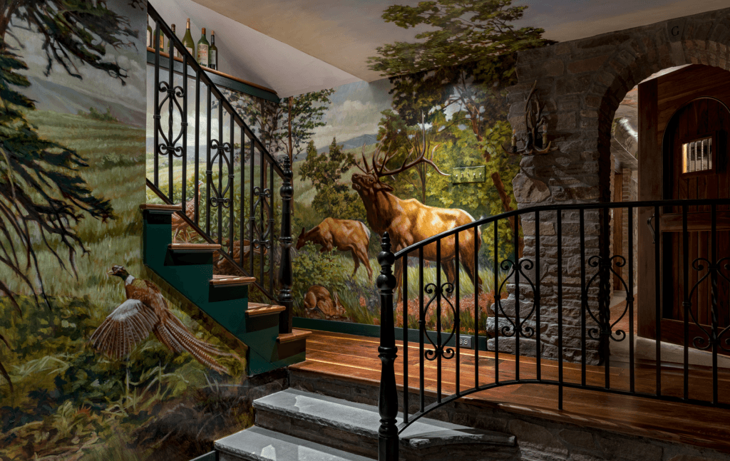 A staircase with a mural depicting elk and pheasants in a forest landscape. forest landscape. The walls are adorned with a detailed mural that includes trees, mountains, and wildlife, creating a rustic and natural ambiance. A wrought-iron railing lines the staircase.