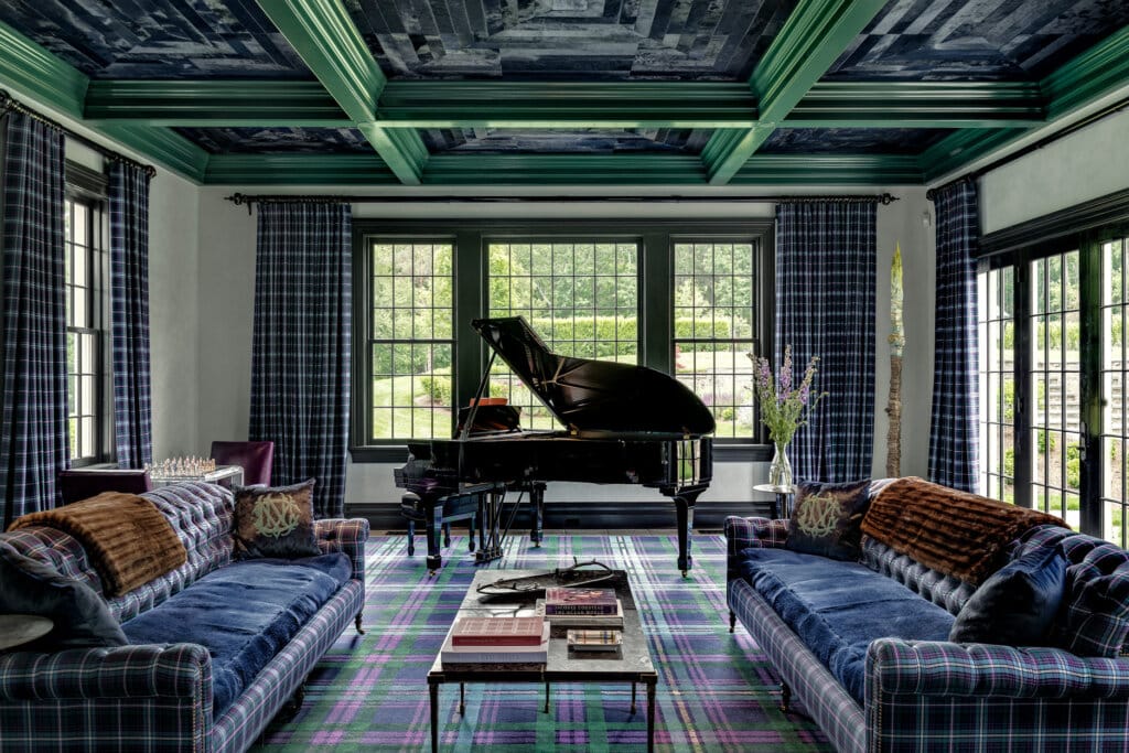 A living room with two plush plaid upholstered sofas, a grand piano, and a tartan rug, featuring plaid curtains and a decorative ceiling.