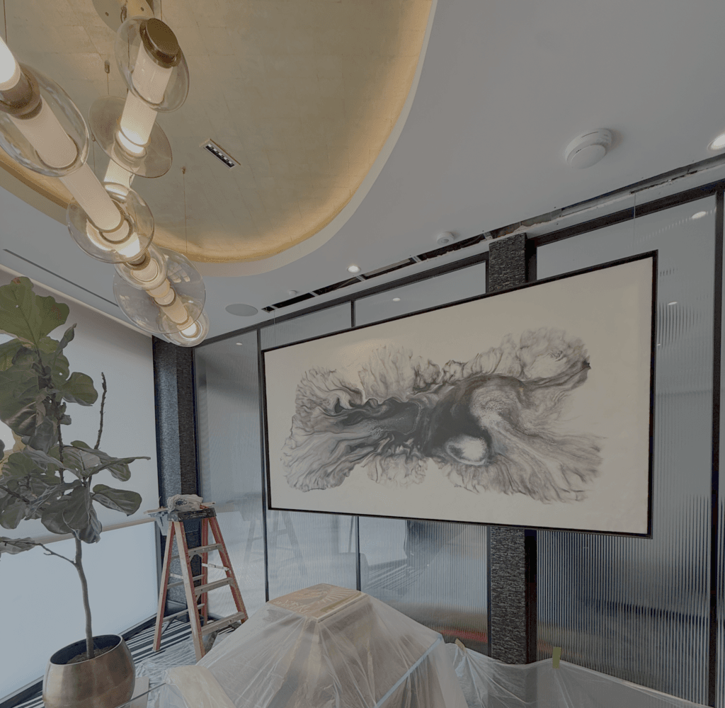 Modern room interior with a large black-and-white animal sketch wall print, tall windows, a red ladder, a potted plant, and warm ceiling pendant lights hanging over a covered work surface.
