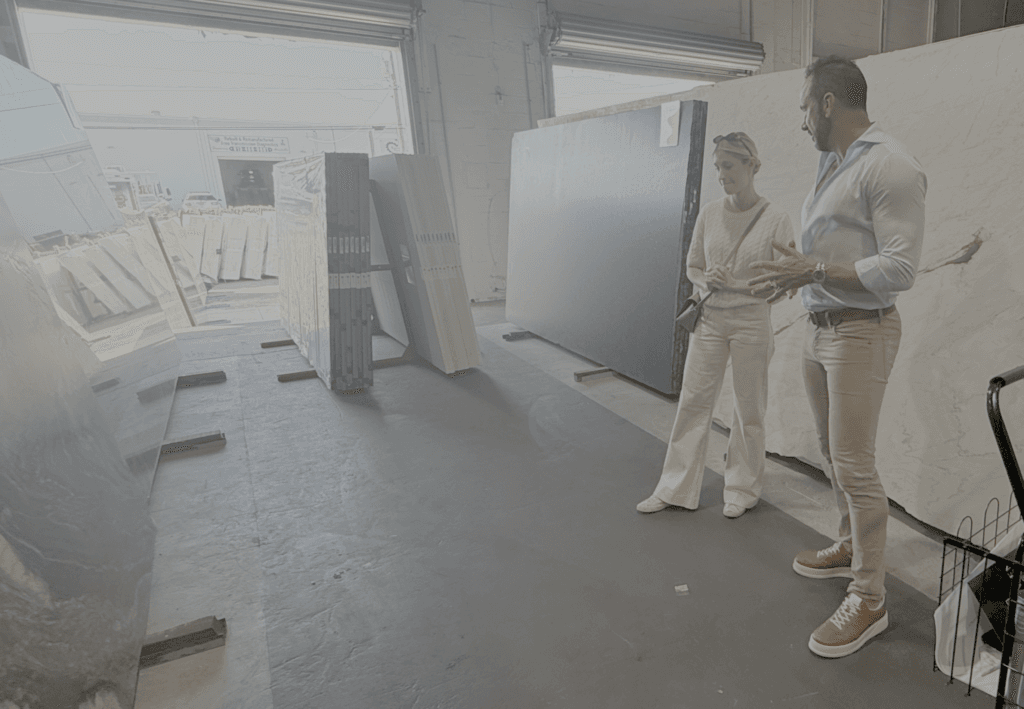 Rob with a client selecting stone slabs in a warehouse with a variety of stone and marble slabs.